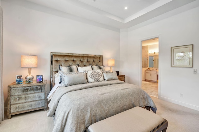 bedroom featuring light colored carpet, baseboards, and ensuite bath