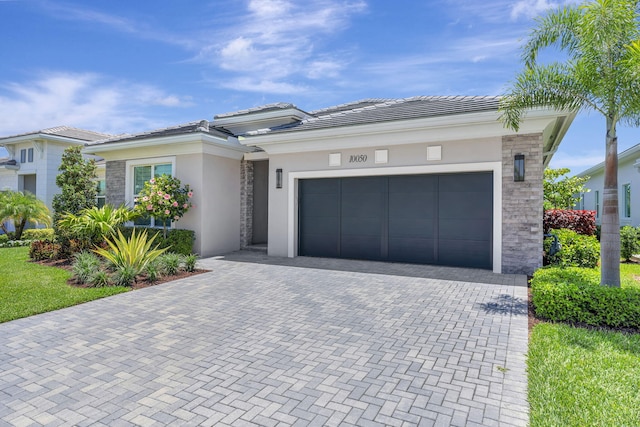 prairie-style house with stucco siding, decorative driveway, a garage, a tile roof, and stone siding
