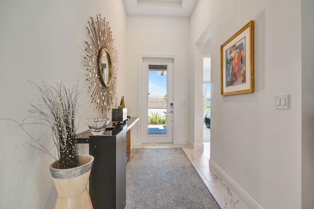 foyer featuring light marble finish flooring and baseboards