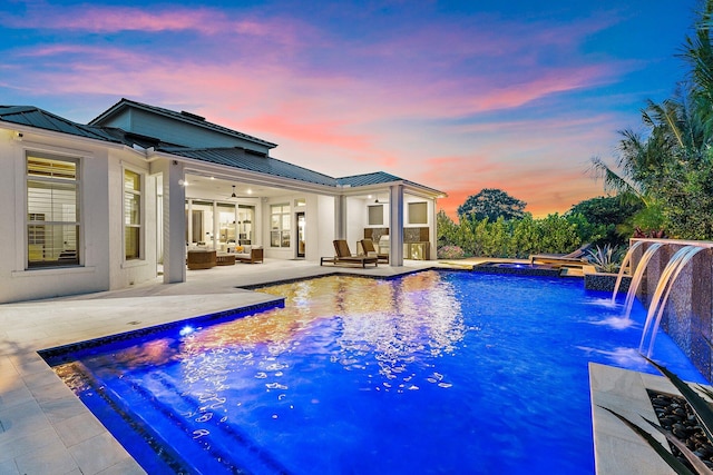 20049 SE Bridgewater Dr, Jupiter, FL 33458 - pool at dusk featuring a jacuzzi, a ceiling fan, a patio area, an outdoor pool, and an outdoor hangout area