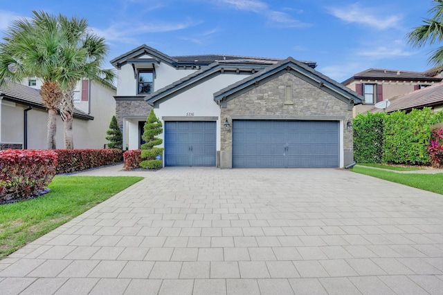 view of front of property with decorative driveway, stone siding, a garage, and stucco siding