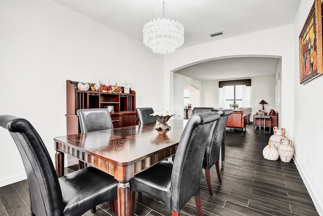 dining room with arched walkways, a chandelier, baseboards, and dark wood-type flooring