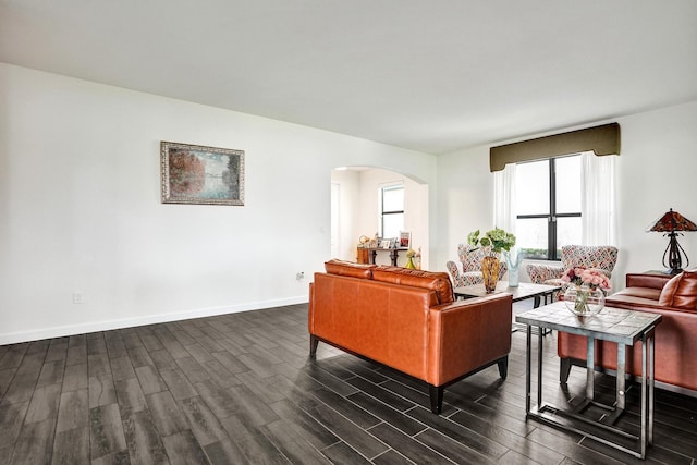 living area with arched walkways, dark wood-style floors, and baseboards