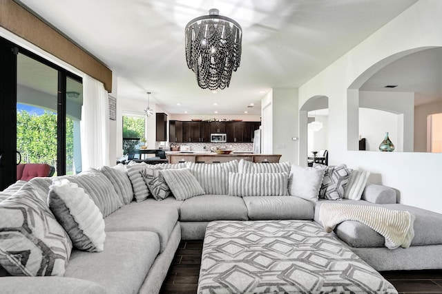 living room featuring arched walkways, dark wood-style flooring, a chandelier, and recessed lighting