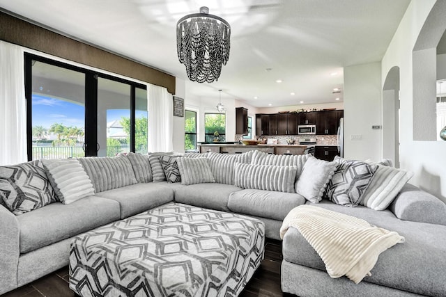 living area with dark wood finished floors, a chandelier, recessed lighting, and arched walkways
