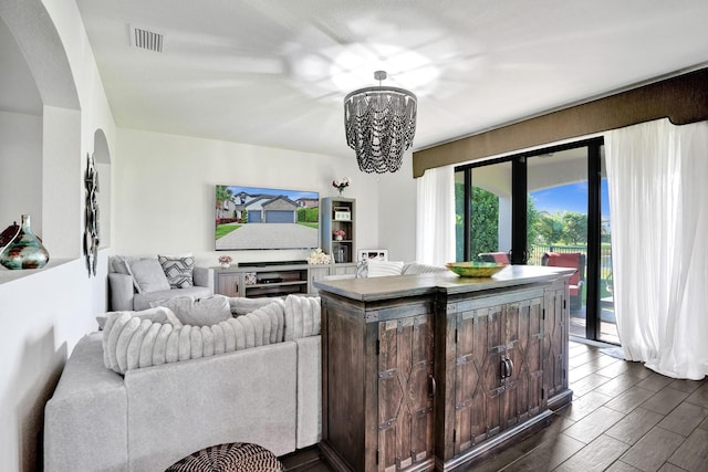 living room featuring arched walkways, a chandelier, and wood finish floors