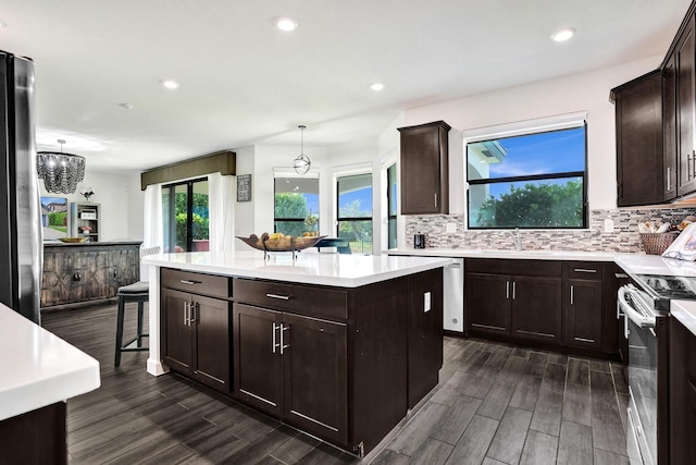 kitchen featuring stainless steel range with electric cooktop, a sink, a center island, dark brown cabinetry, and recessed lighting
