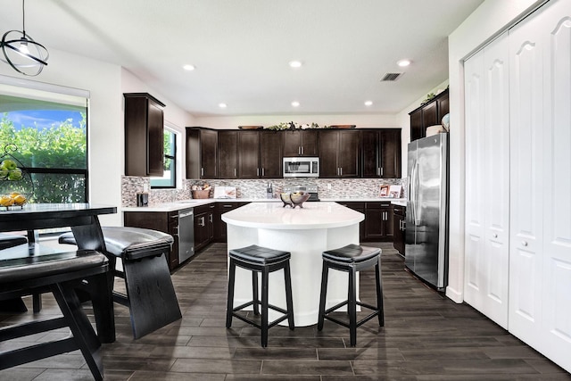 kitchen featuring appliances with stainless steel finishes, a center island, light countertops, backsplash, and recessed lighting