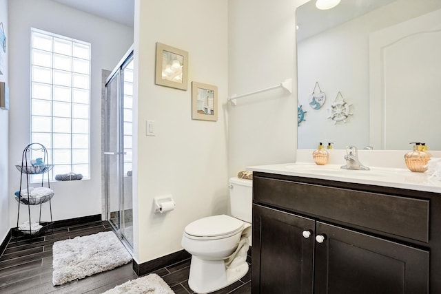 full bathroom with wood tiled floors, a stall shower, toilet, vanity, and baseboards