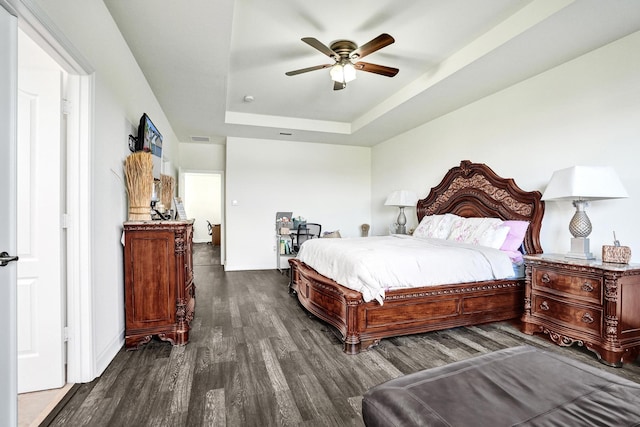 bedroom featuring wood finished floors, a raised ceiling, and a ceiling fan