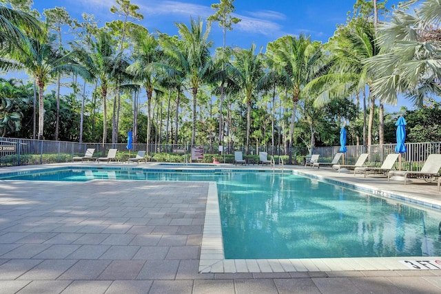 community pool featuring fence, a patio area, and view of scattered trees