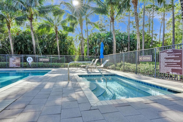 community pool with fence, a patio, and view of wooded area