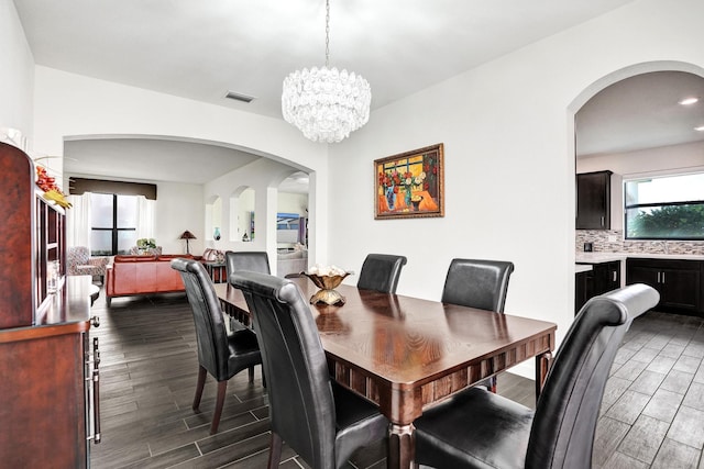 dining room featuring wood tiled floors, a chandelier, arched walkways, and recessed lighting