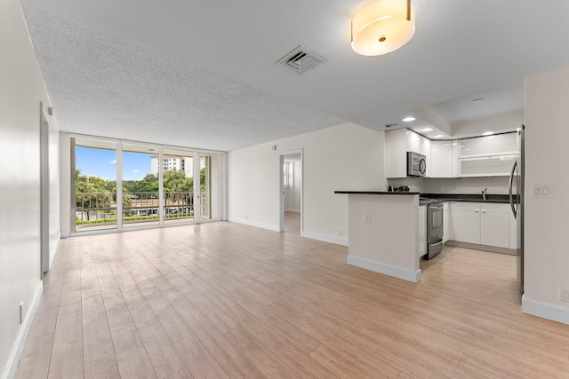 kitchen with stainless steel appliances, open floor plan, floor to ceiling windows, dark countertops, and open shelves