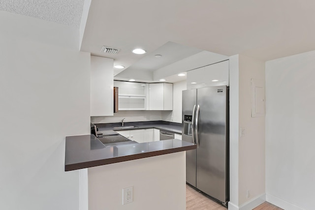 kitchen with stainless steel appliances, dark countertops, a peninsula, a sink, and recessed lighting