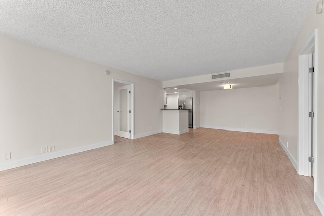 unfurnished living room featuring light wood-style floors, a textured ceiling, and baseboards