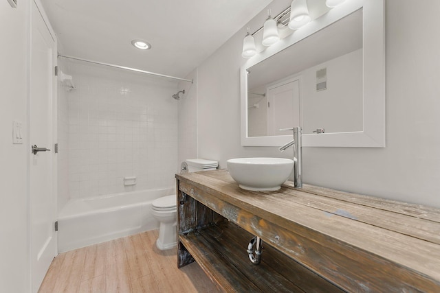 full bathroom with toilet, wood finished floors, recessed lighting, vanity, and washtub / shower combination