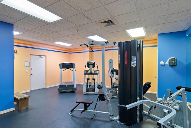 exercise room with baseboards and a paneled ceiling