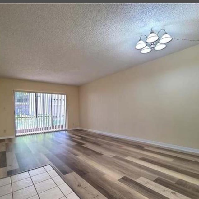 4155 NW 90th Ave Unit 106, Coral Springs, FL 33065 - unfurnished room featuring a textured ceiling, baseboards, a chandelier, and wood finished floors
