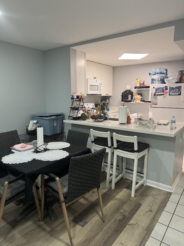 4155 NW 90th Ave Unit 106, Coral Springs, FL 33065 - kitchen featuring white appliances, light wood-style floors, a peninsula, a kitchen breakfast bar, and light countertops