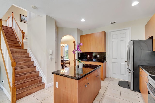 116 Ibisca Ter, Royal Palm Beach, FL 33411 - kitchen featuring a center island, dark stone counters, arched walkways, light tile patterned floors, and recessed lighting