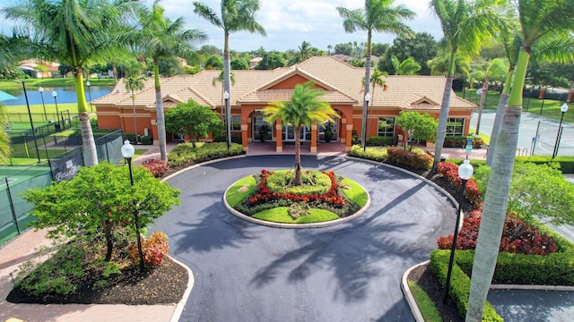 116 Ibisca Ter, Royal Palm Beach, FL 33411 - view of front of house featuring curved driveway, a tile roof, a water view, and stucco siding