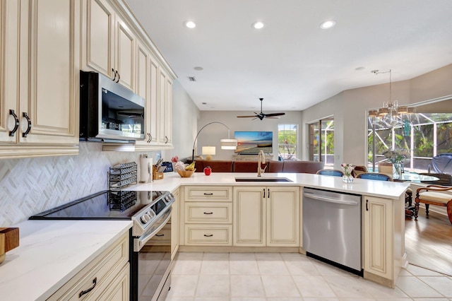 2211 Vero Beach Ln, West Palm Beach, FL 33411 - kitchen with cream cabinets, stainless steel appliances, a sink, decorative backsplash, and recessed lighting