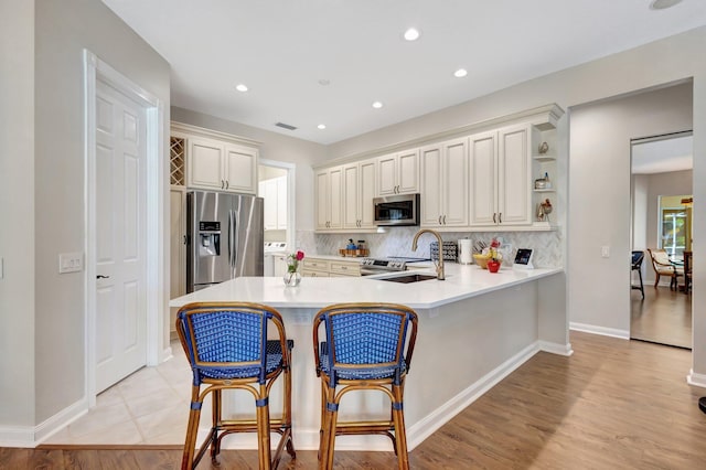 2211 Vero Beach Ln, West Palm Beach, FL 33411 - kitchen with appliances with stainless steel finishes, a sink, a peninsula, light countertops, and tasteful backsplash