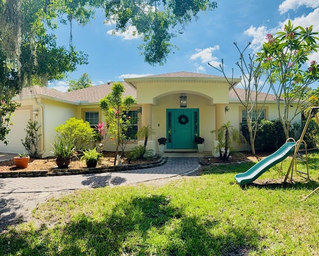 1325 Bennett Rd, Fort Pierce, FL 34947 - view of front facade with stucco siding, a front yard, an attached garage, and a playground
