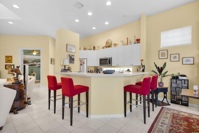 kitchen with appliances with stainless steel finishes, a kitchen bar, a peninsula, white cabinets, and recessed lighting