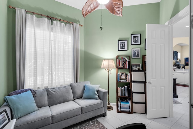 tiled living area with arched walkways and ceiling fan