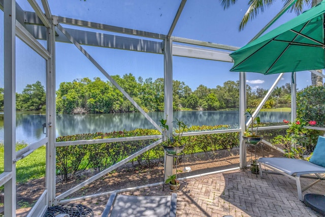 sunroom with a water view and view of wooded area