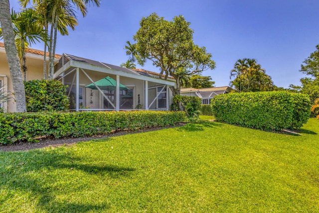 view of green lawn with a lanai