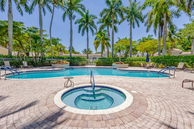 community pool featuring fence, a patio area, and a hot tub