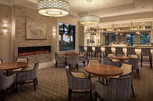dining space with wet bar, a fireplace, ornamental molding, and baseboards