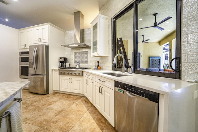 kitchen with appliances with stainless steel finishes, a sink, wall chimney range hood, a ceiling fan, and backsplash