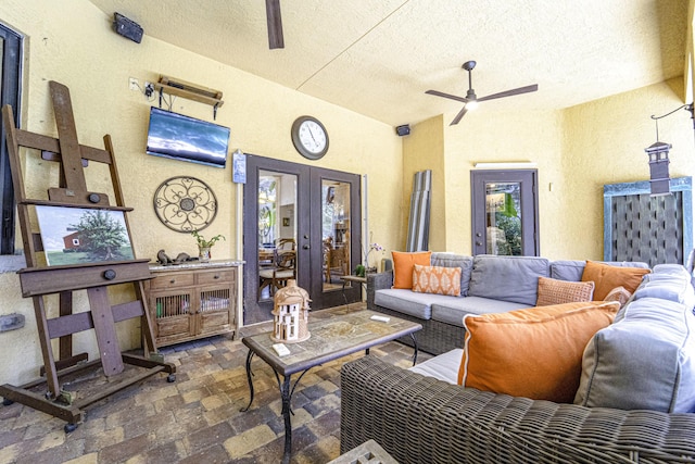 living area featuring french doors, a textured ceiling, and ceiling fan