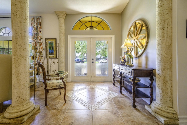 foyer featuring french doors, ornate columns, and tile patterned floors