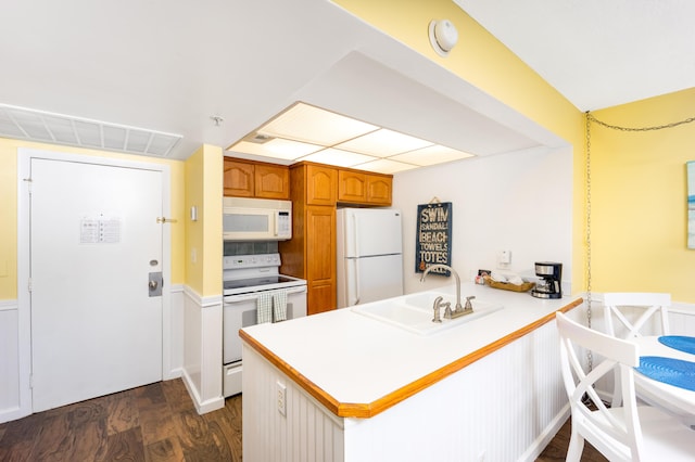 9800 S Ocean Dr Unit 415, Jensen Beach, FL 34957 - kitchen featuring white appliances, a sink, a peninsula, dark wood finished floors, and brown cabinets