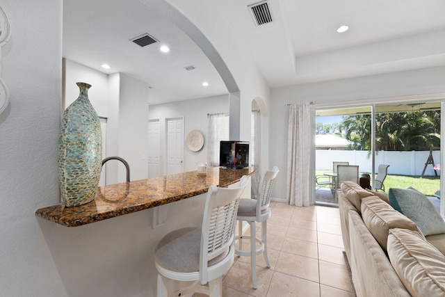 3552 SW Dellamano St, Port Saint Lucie, FL 34953 - kitchen featuring dark stone counters, arched walkways, open floor plan, recessed lighting, and a kitchen breakfast bar