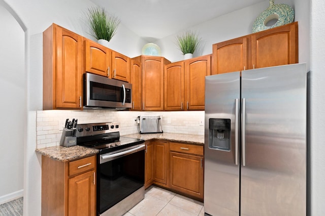 3552 SW Dellamano St, Port Saint Lucie, FL 34953 - kitchen featuring stainless steel appliances, tasteful backsplash, light stone countertops, and brown cabinetry