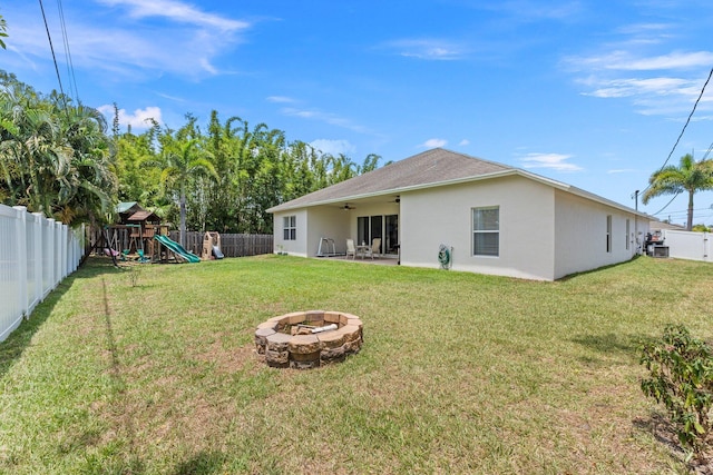 3552 SW Dellamano St, Port Saint Lucie, FL 34953 - back of house featuring ceiling fan, stucco siding, a fire pit, and a playground