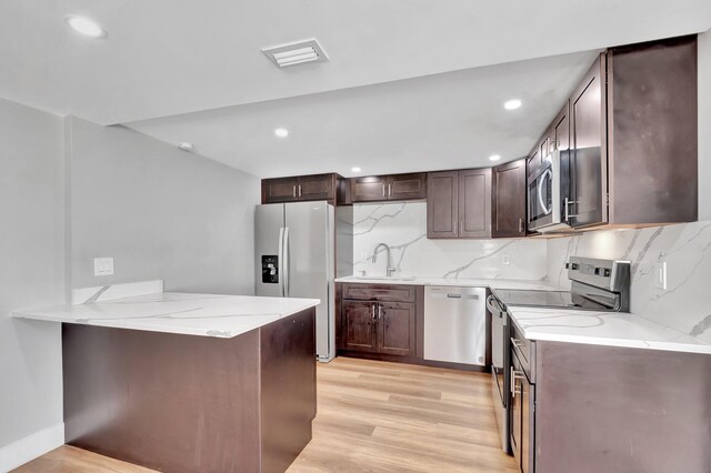 125 E Hart St, Lantana, FL 33462 - kitchen with stainless steel appliances, light stone counters, a sink, backsplash, and dark brown cabinets