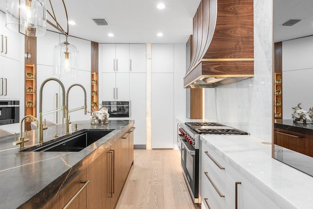 17709 Circle Pond Ct, Boca Raton, FL 33496 - kitchen featuring high end range, a sink, light wood-style flooring, dark stone countertops, and pendant lighting