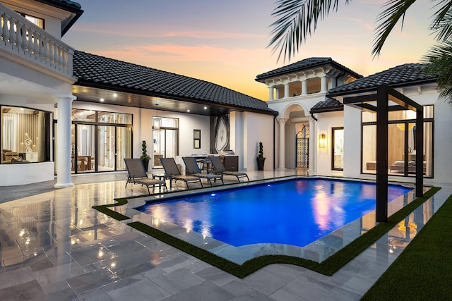 17709 Circle Pond Ct, Boca Raton, FL 33496 - back of house at dusk with a tile roof, stucco siding, a patio, and an outdoor pool
