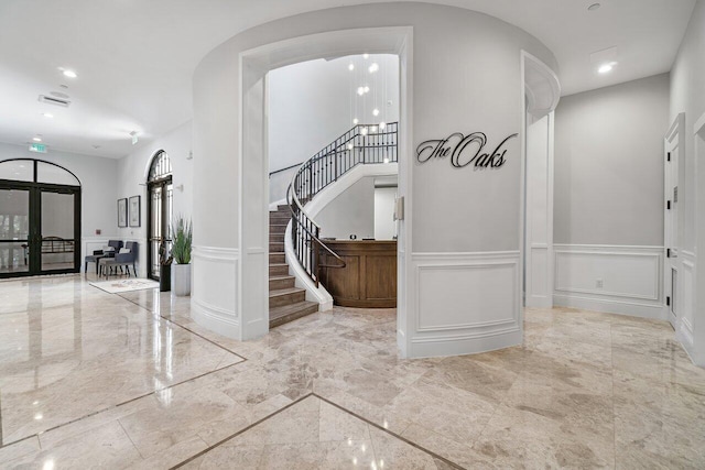 17709 Circle Pond Ct, Boca Raton, FL 33496 - hall with a decorative wall, marble tiled floors, stairway, a wainscoted wall, and french doors
