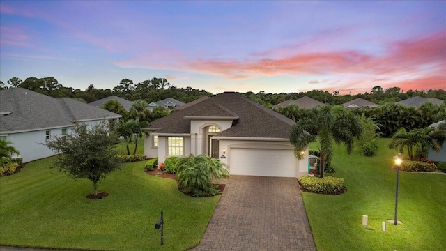 8369 Paladin Sq, Vero Beach, FL 32967 - view of front facade featuring a garage, decorative driveway, stucco siding, a yard, and roof with shingles
