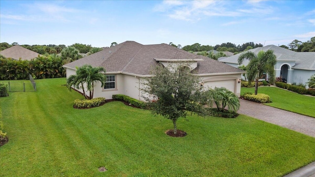 8369 Paladin Sq, Vero Beach, FL 32967 - view of front of house with a garage, a front yard, driveway, stucco siding, and roof with shingles