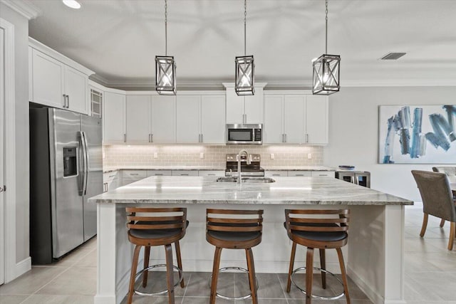 8369 Paladin Sq, Vero Beach, FL 32967 - kitchen with stainless steel appliances, a sink, backsplash, white cabinets, and a center island with sink