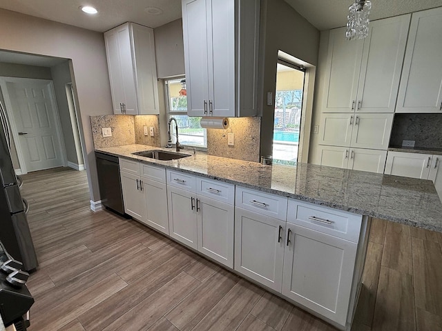 1807 Crafton Rd, North Palm Beach, FL 33408 - kitchen with black dishwasher, a sink, white cabinetry, wood finished floors, and light stone countertops